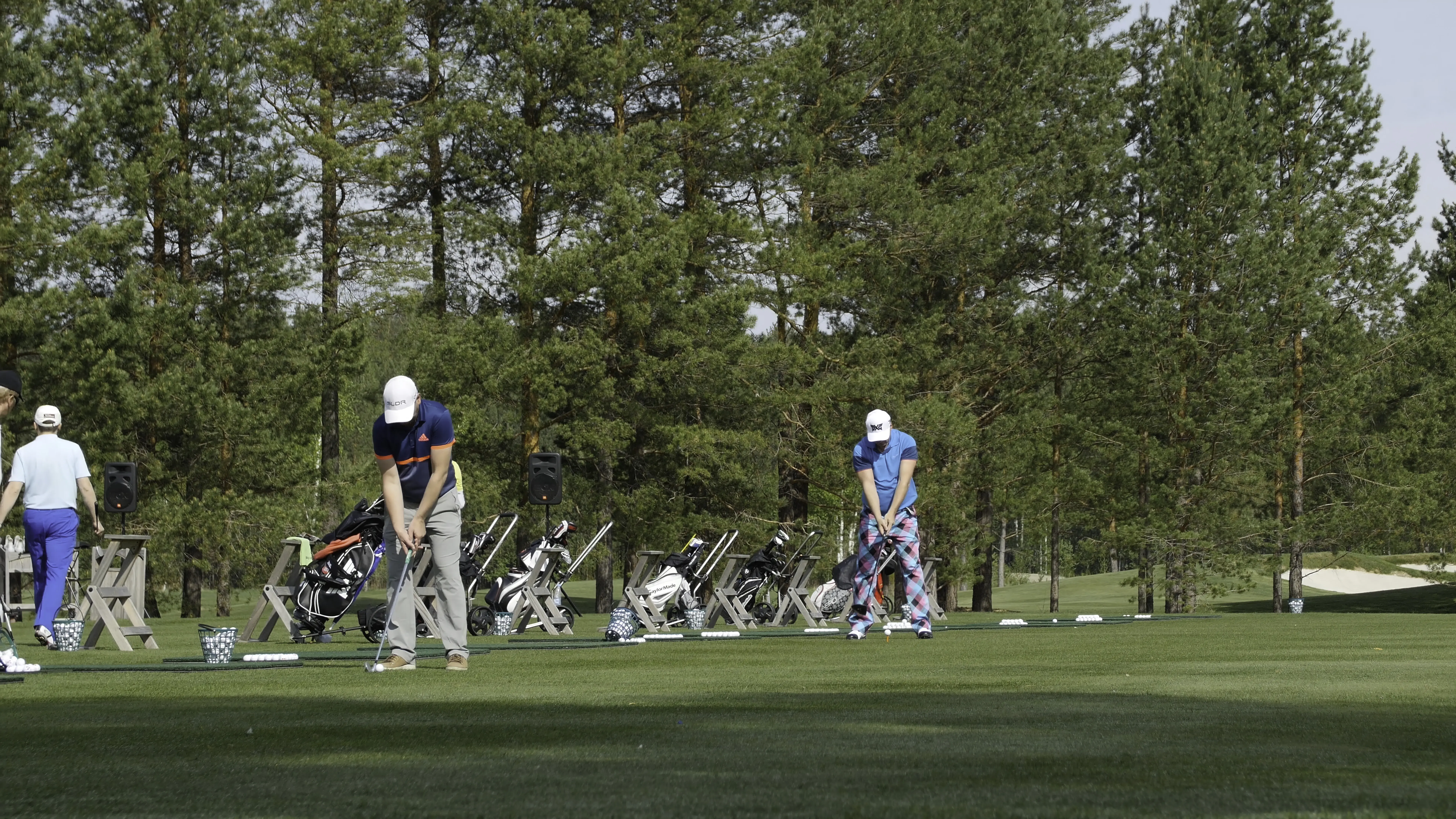 Golfers play the game of golf on a sweeping golf course in summer.