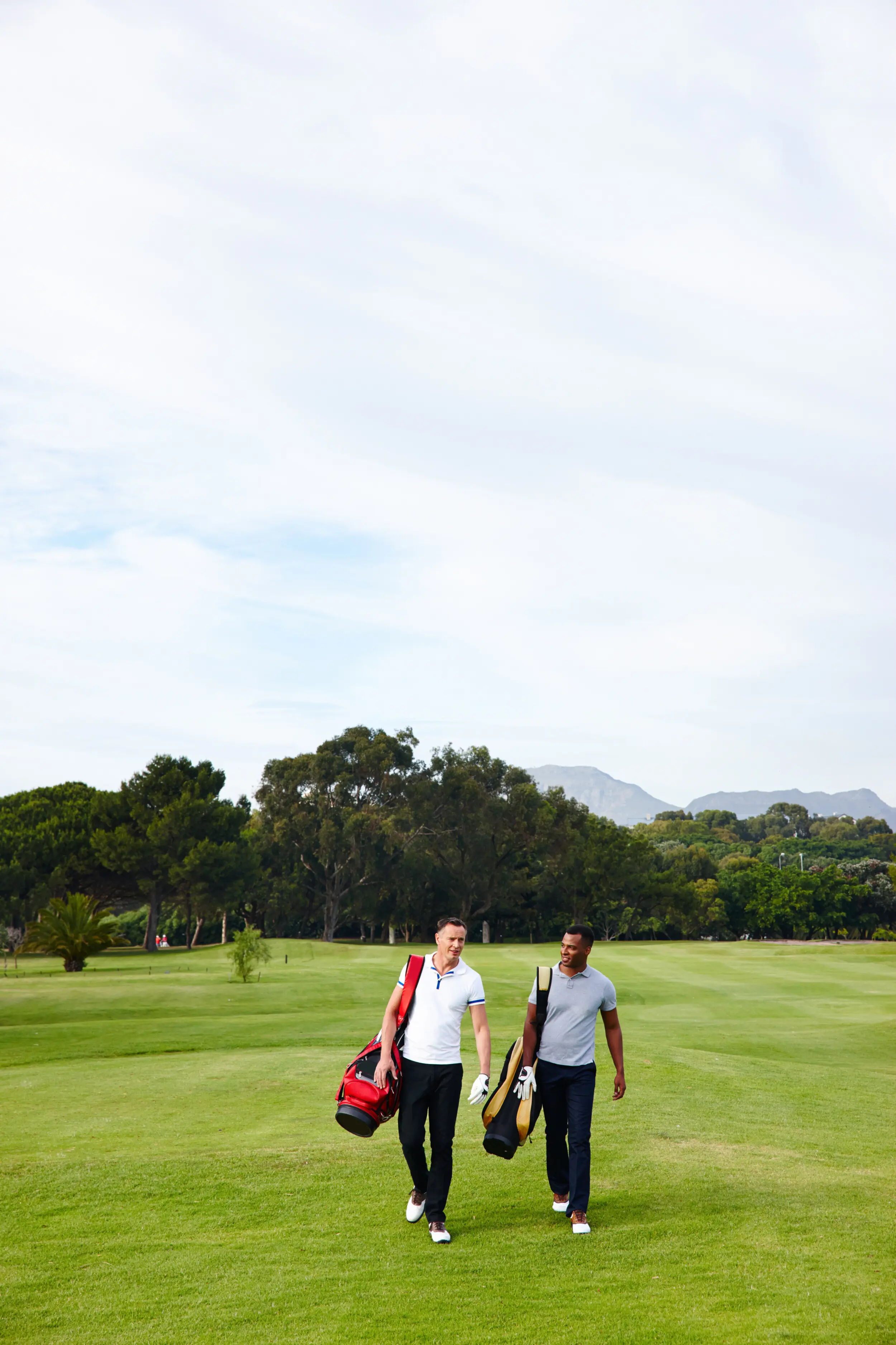 Friends and the sport of golf on the field and golf course for a game, match, and competition; a recreational hobby with men walking on the grass with a driver for training, fitness, and outdoor practice for fun.